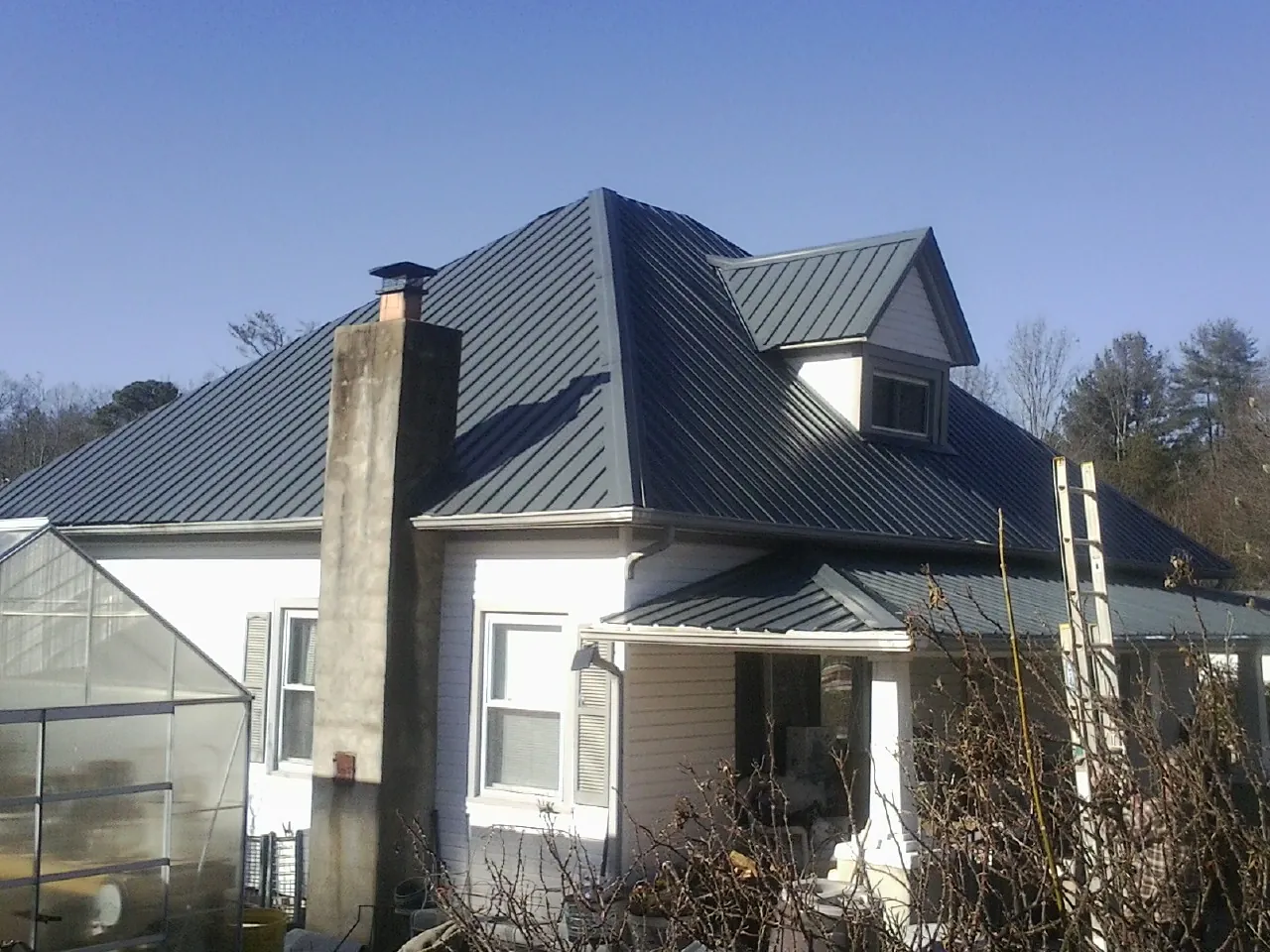 Dark blue standing seam metal roof on a white farmhouse with dormer — Slate & Tile Roof Repair by Roofing Brothers in Hutchinson
