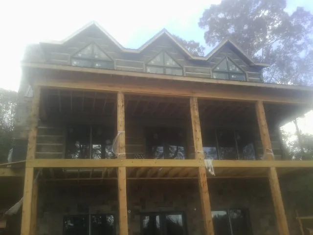 Dormers and porch framing on a large log home under construction — Roof Coating work by our crew in Hutchinson