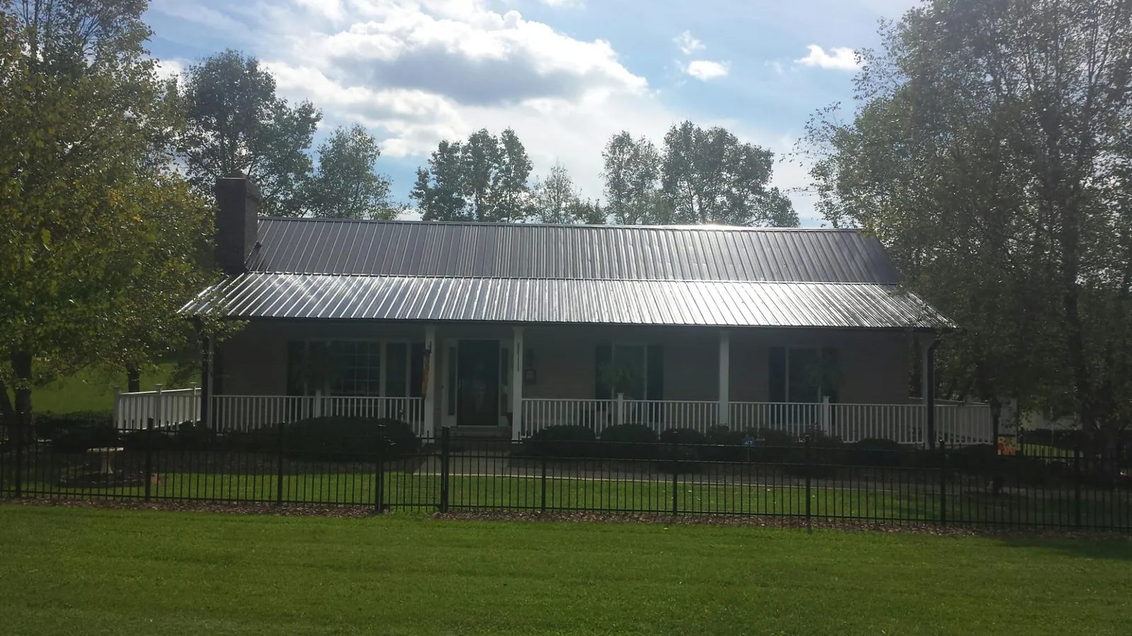 Gray metal roof on a brick ranch with a full width front porch — Gutter Guard Installation work by our crew in Hutchinson