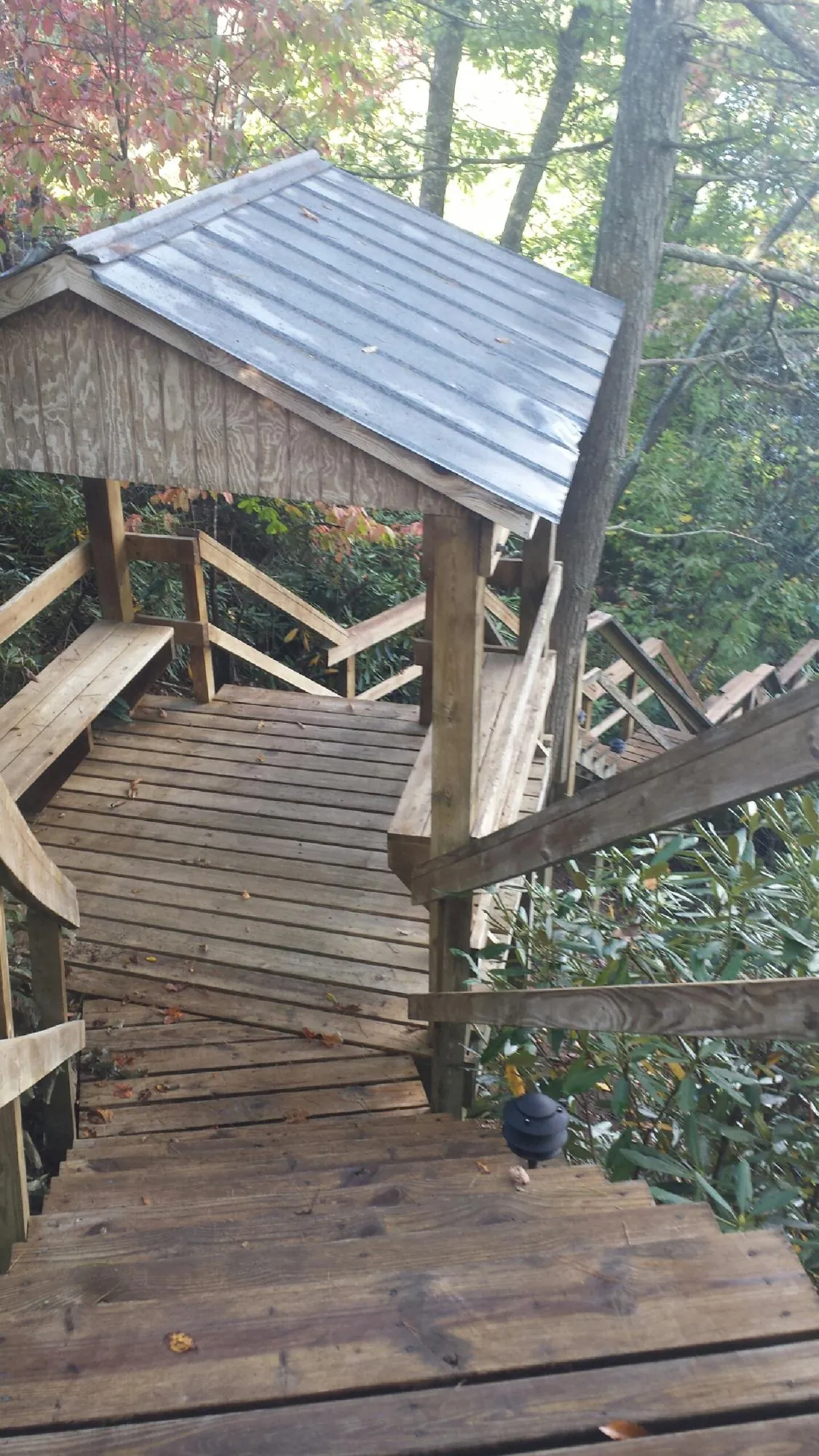 Metal roofed shelter over wooden steps on a wooded walkway — Skylight Repair & Installation work by our crew in Hutchinson