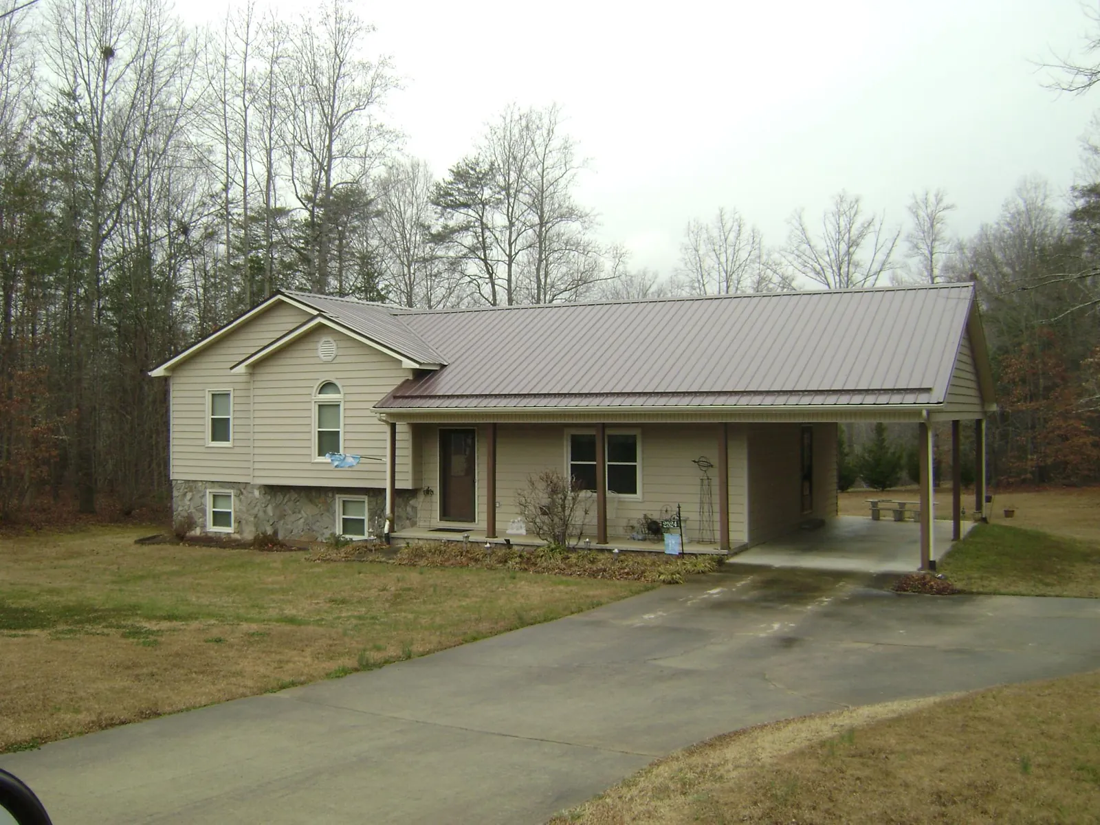 Brown metal roof on a tan split level home with an attached carport in Hutchinson
